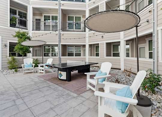 A patio with a table and chairs and a white umbrella.