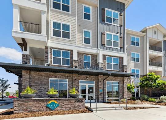 A multi-story apartment building with a stone base and balconies.
