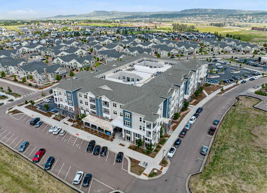 A large apartment complex with a parking lot in front.