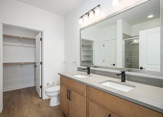 A bathroom with a toilet, sink, and mirror.