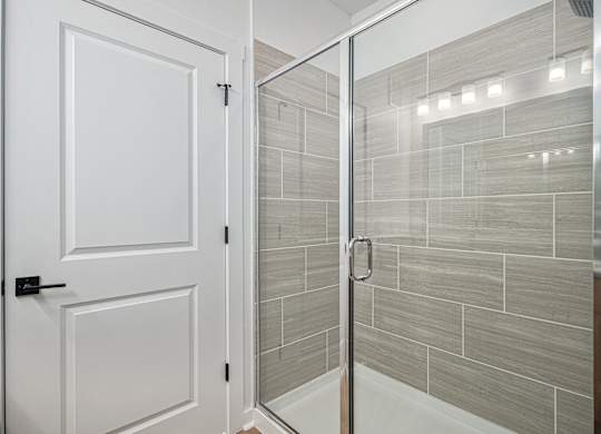 A white door is open to a tiled shower.