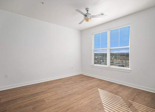 A room with a ceiling fan and a window with blinds.