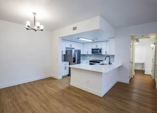 A kitchen with white cabinets and a wooden floor.
