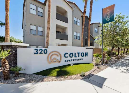 Colton Apartments building with a flag and palm trees in front.
