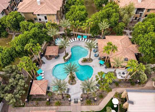 An aerial view of a pool surrounded by palm trees and buildings.
