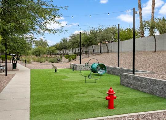 A red fire hydrant is in a grassy area with a green trash can and a green metal chair.