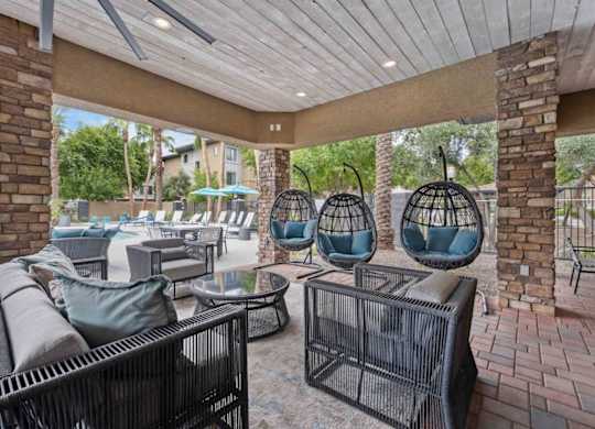 A patio with a black wicker sofa and chairs.