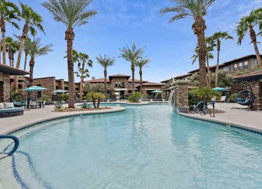 A swimming pool surrounded by palm trees and lounge chairs.
