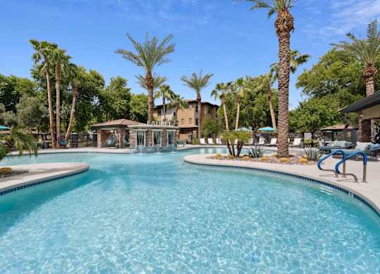 A large swimming pool surrounded by palm trees and lounge chairs.