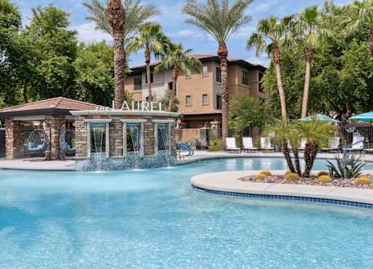 A pool with a waterfall and a building named Laurel in the background.