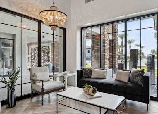 A modern living room with a black couch, a white coffee table, and a large window.