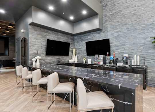 A modern kitchen with a marble countertop and bar stools.