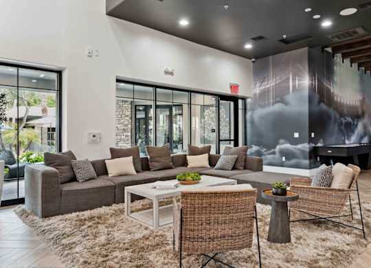 A modern living room with a grey sofa, a white coffee table, and a woven chair.