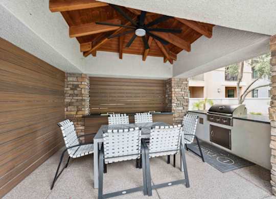 A patio with a table and chairs and a grill.
