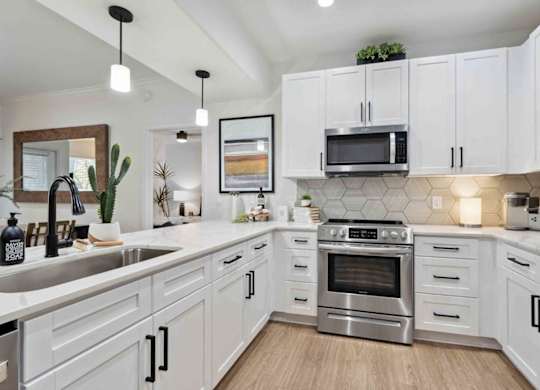 A modern kitchen with white cabinets and stainless steel appliances.