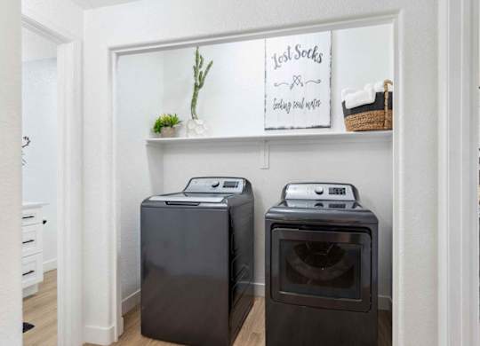 Two black front load washing machines in a laundry room.