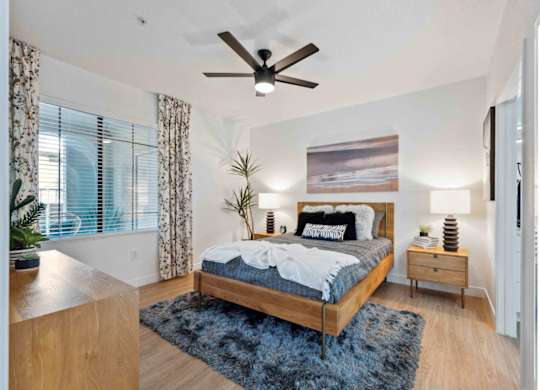 A bedroom with a bed, nightstands, and a ceiling fan.