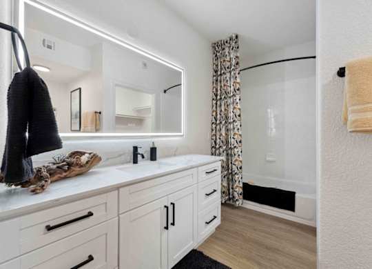 A bathroom with a white vanity and a mirror above it.