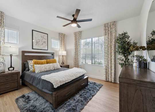 A bedroom with a bed, nightstands, and a ceiling fan.
