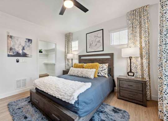 A bedroom with a bed, nightstand, and a ceiling fan.