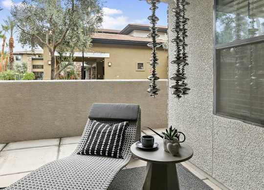 A grey chair with a black cushion is on a patio.