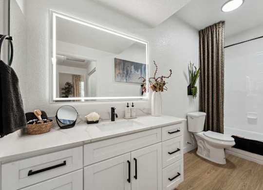 A bathroom with a white countertop and a white toilet.