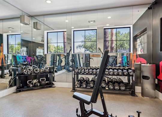 A gym with a variety of equipment including dumbbells and weight machines.