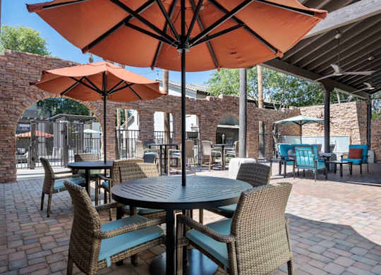 A patio with tables and chairs under umbrellas.