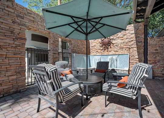 A patio with a table and chairs under an umbrella.