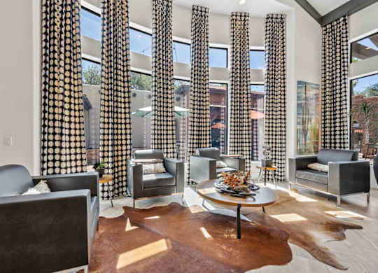 A living room with a cowhide rug and a glass table with a vase of flowers on it.
