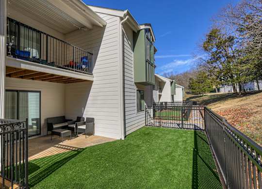 A balcony with a table and chairs overlooks a green lawn.