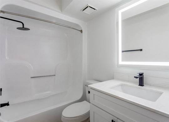 A white bathroom with a toilet, sink, and shower.