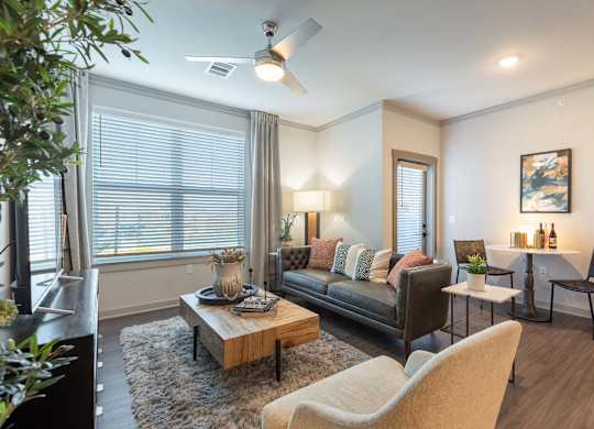 A living room with a brown couch, a coffee table, and a ceiling fan.