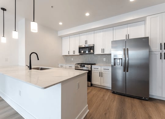A modern kitchen with a white countertop and stainless steel appliances.