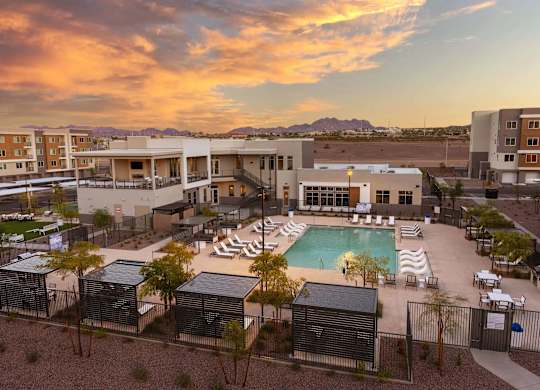 A resort with a pool and a sunset in the background.