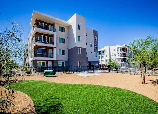 A modern multi-story building with a green lawn in front.