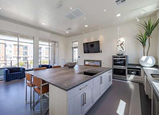 A modern kitchen with a large island and a flat screen TV mounted on the wall.