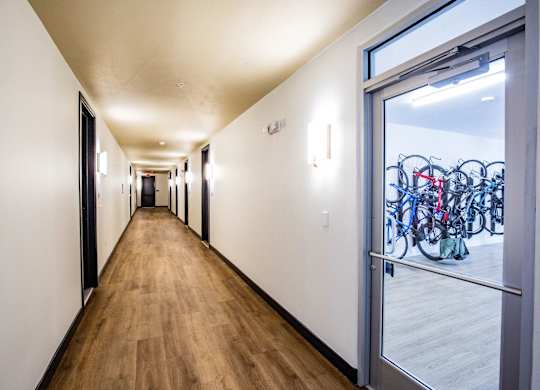 A hallway with a glass door leading to a bicycle storage room.
