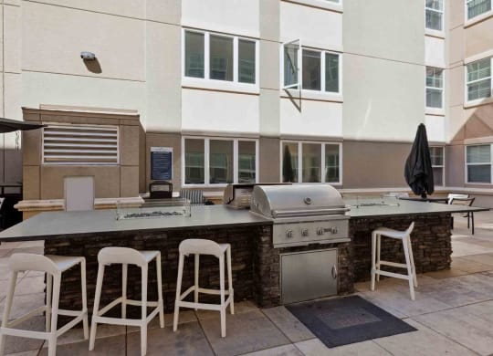 a patio with a barbecue grill and tables and chairs