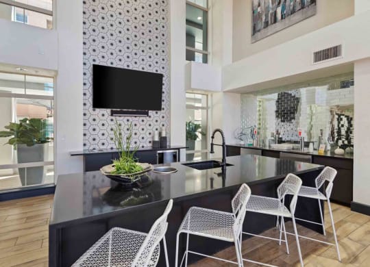 a kitchen with a large center island with a black countertop and white chairs