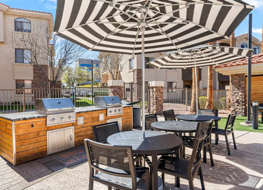 A patio with a table and chairs under a striped umbrella.