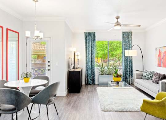 A living room with a white couch, a yellow chair, and a dining table with chairs.