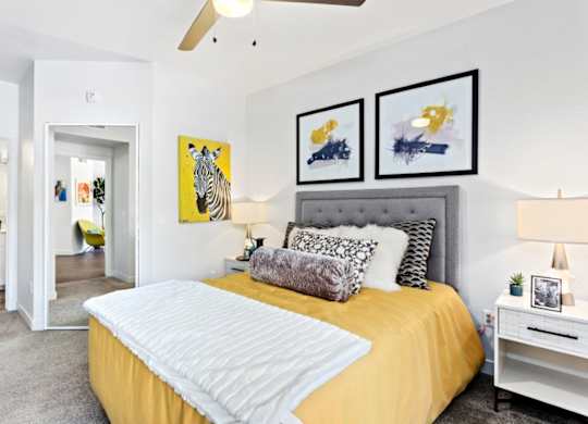 A bedroom with a bed, nightstand, and two framed pictures on the wall.