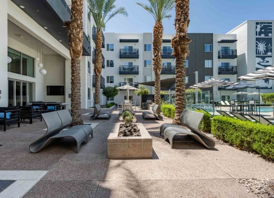 a patio with lounge chairs and a fire pit in front of a slate scottsdale apartment building