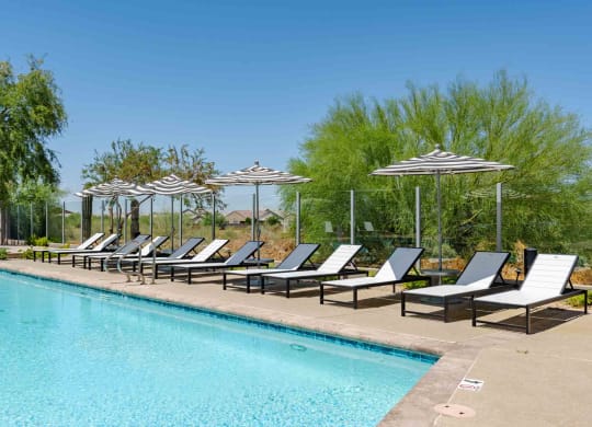 a swimming pool with chaise lounge chairs and umbrellas