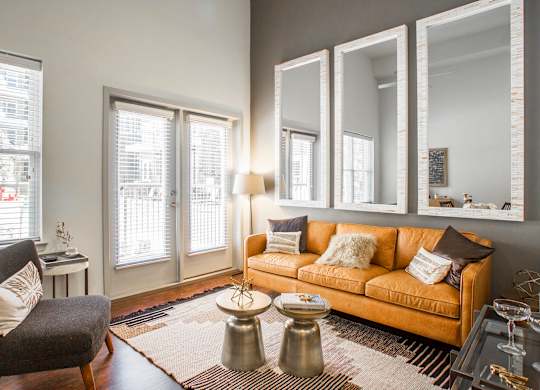 A living room with a couch, chair, and mirrors.