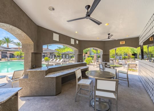 a patio with tables and chairs and a pool in the background