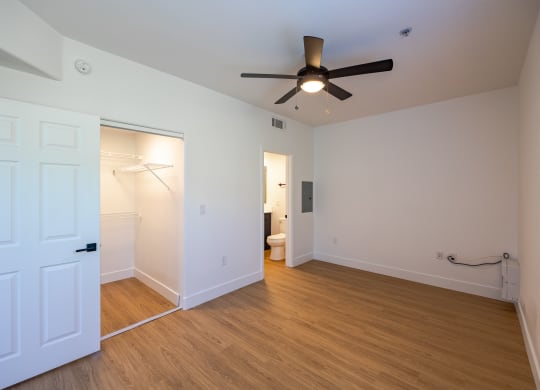 a bedroom with white walls and a ceiling fan
