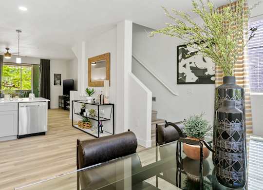 a living room with a glass table and a kitchen