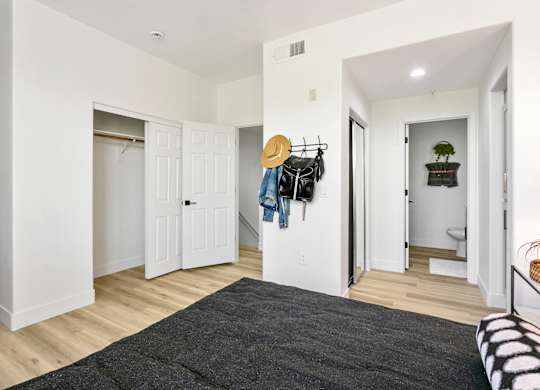 a bedroom with white walls and white closets and a gray rug